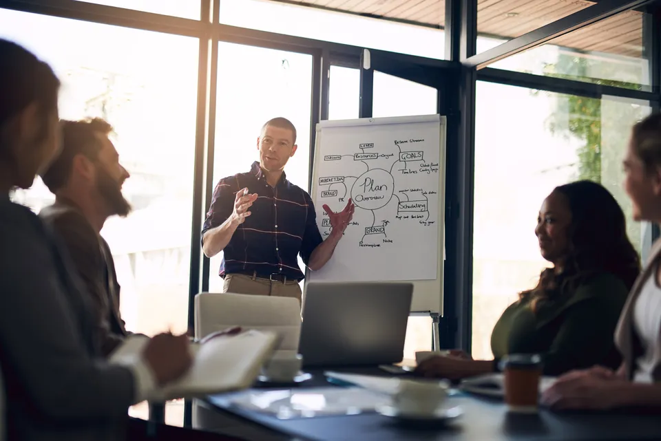 Trainer moderiert eine Besprechung an einem Whiteboard